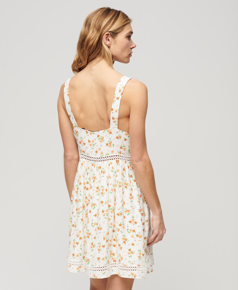 cami-jurk met v-hals en kanten afwerking in wit met een speels bloemenpatroon.